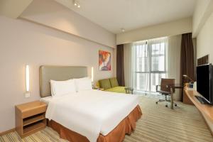 a hotel room with a large bed and a television at Holiday Inn Express Shanghai Gongkang, an IHG Hotel in Baoshan