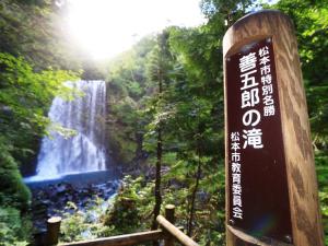 ein Schild vor einem Wasserfall in einem Wald in der Unterkunft Guesthouse Tomoshibi in Matsumoto