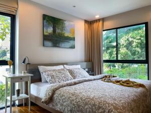 a bedroom with a large bed and large windows at Title Rawai Phase III by Beringela in Rawai Beach