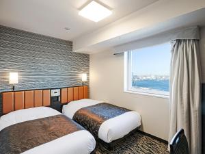 a hotel room with two beds and a window at APA Hotel & Resort Yokohama Bay Tower in Yokohama