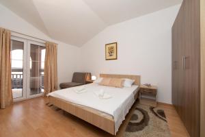 a bedroom with a bed and a chair and a window at Apartments Simovic in Tučepi