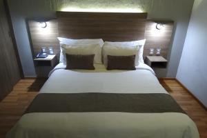a bedroom with a large white bed with two night stands at Hotel Villa Del Sol Expo in Guadalajara