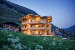 a large wooden house on a hill at night at Haus Alpenprinzessin in Neustift im Stubaital