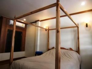 a wooden four poster bed in a bedroom at The Royal ThaTien Village in Bangkok