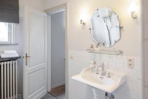 a white bathroom with a sink and a mirror at B&B La Passion Interdite in Ostend