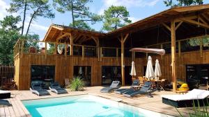 a house with a pool and chairs and a patio at Ô Lac in Lacanau