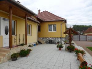 Casa amarilla con patio con plantas y flores en Napfény Apartman és Vendégház, en Egerszalók