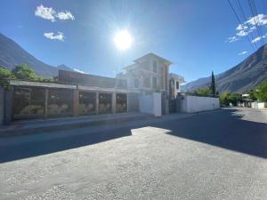 ein Gebäude auf einer Straße mit der Sonne am Himmel in der Unterkunft ISLE OF HIGHLAND TOURS Guest House in Gilgit