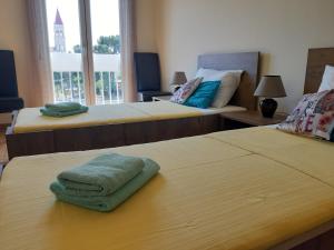 Cette chambre comprend 2 lits et une serviette verte sur une table. dans l'établissement Apartman Petrovic CITY CENTER TROGIR, à Trogir