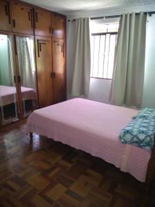 um quarto com uma cama com uma colcha rosa em Pousada Santa Felicidade com garagem J em Curitiba