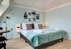 a bedroom with a large bed and a table at Hotel Duinlust in Domburg