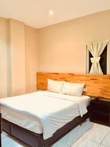 Un dormitorio con una gran cama blanca y una ventana en Hotel Anda en Pematangsiantar