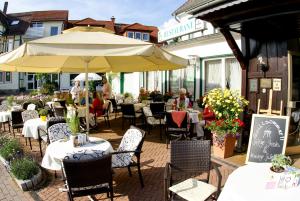 un patio con mesas, sillas y una sombrilla en Hotel Riemann en Bad Lauterberg