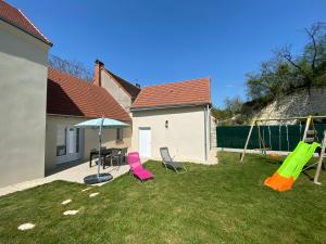 a yard with a playground with chairs and an umbrella at Gîte Bambou in Seigy