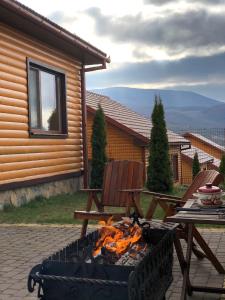 a fire pit in a patio with a table and chairs at Solnce Karpat in Polyana