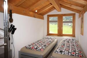クロスタースにあるGotschnablickのベッド2台と窓が備わる客室です。