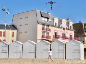 a woman is flying a kite on the beach at Hôtel Outre-Mer - Villa Le Couchant in Villers-sur-Mer