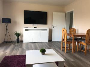 ein Wohnzimmer mit einem Tisch und einem TV an der Wand in der Unterkunft Ferienwohnung Aueblick Kassel in Kassel
