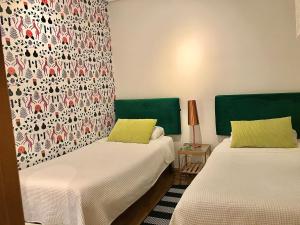 2 Betten mit grünen Kopfteilen in einem Zimmer in der Unterkunft Pasaje al Pilar in Saragossa