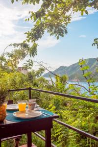 una mesa con 2 tazas de zumo de naranja en el balcón en Casa de Piedra Taganga en Taganga