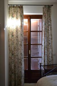 a bedroom with a window and a door with curtains at La Locanda di Valbella in Asti
