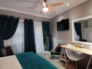 - une chambre avec un lit et un ventilateur de plafond dans l'établissement Roxy's Rest Guest House, à Vanderbijlpark