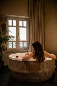 una donna seduta in una vasca da bagno in una stanza di Divino Suites Chania a Chania