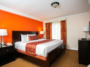 1 dormitorio con 1 cama grande y pared de color naranja en The Wilshire Grand Hotel, en West Orange