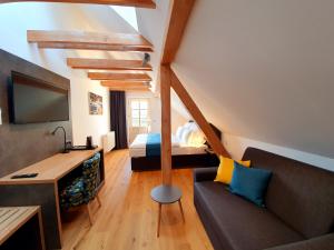 a living room with a couch and a bed in a room at Hotel KORTUS in Jetřichovice