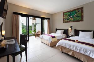 a hotel room with two beds and a desk and a desk at Kebun Villas & Resort in Senggigi