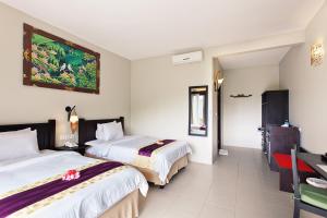 
a hotel room with a bed, desk and a painting on the wall at Kebun Villas & Resort in Senggigi
