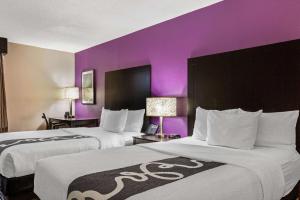 two beds in a hotel room with purple walls at La Quinta by Wyndham Miami Lakes in Miami Lakes +19 photos