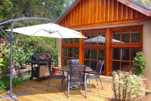 a patio with a table and a grill and an umbrella at BEAUTIFUL RETREAT - 20 mins to CBD and only 10 mins to MONA! in Collinsvale