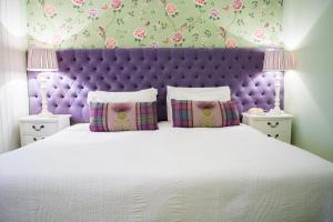 a bedroom with a large bed with a purple headboard at Beachlands Hotel in Weston-super-Mare