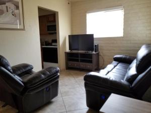 a living room with two leather couches and a flat screen tv at Tucson Airport Oasis in Tucson