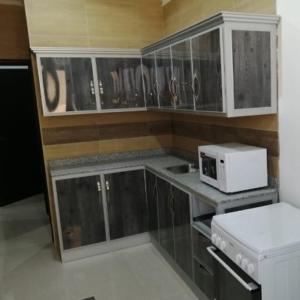 cocina con armarios de madera y microondas en Ras Alkhyran Resort عائلات فقط en An Nāmī