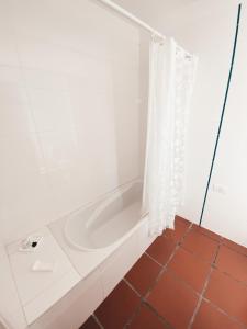 El baño incluye bañera blanca con cortina de ducha. en La Norita en Balcarce