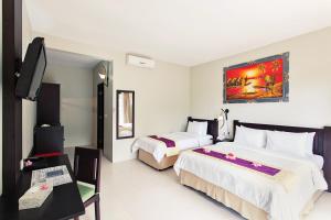a hotel room with two beds and a flat screen tv at Kebun Villas & Resort in Senggigi
