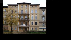 un gran edificio de apartamentos con un árbol delante en Apartament Turkusowy, en Jelenia Góra