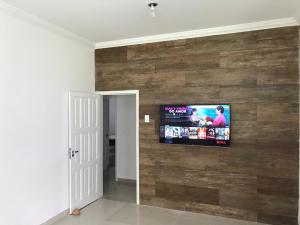 a living room with a tv on a wooden wall at Ampla Casa na beira mar de Maragogi in Maragogi