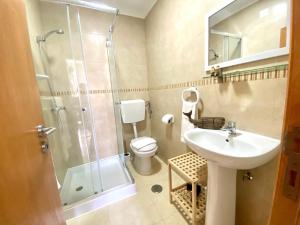 a bathroom with a toilet and a sink and a shower at Pátio Abílio Guest House in Nazaré +31 photos