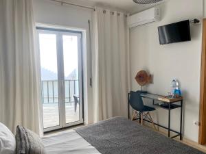 a bedroom with a bed and a desk and a window at Pátio Abílio Guest House in Nazaré