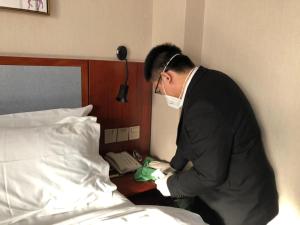 a man wearing a mask standing next to a bed at Mengguo Hotel Pudong Airport in Shanghai