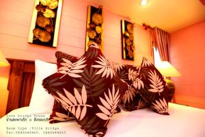 a bedroom with a bed with two pillows on it at Love Bridge House บ้านสะพานรัก in Sangkhla Buri