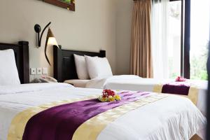 a hotel room with two beds with flowers on it at Kebun Villas & Resort in Senggigi