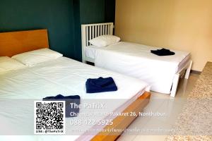 two beds in a room with blue towels on them at The PaTriX Chaengwattana in Nonthaburi