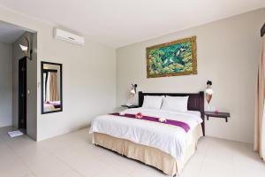 
a bedroom with a bed and a painting on the wall at Kebun Villas & Resort in Senggigi
