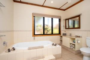 
a bathroom with a tub, toilet, sink and bathtub at Bali Hai Resort & Spa in Broome
