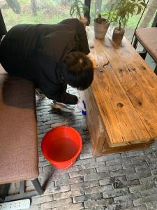 a person bending over a wooden table next to a red bowl at Shanghai Daoli one step garden(PVG&International Resort) in Shanghai