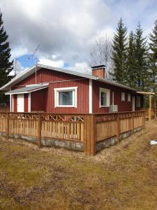 a red house with a wooden fence around it at Järvitalo in Soini +7 photos